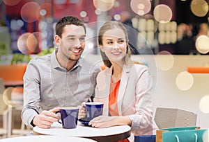 Happy couple with shopping bags drinking coffee