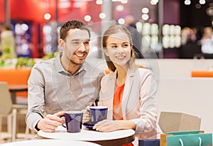 Happy couple with shopping bags drinking coffee