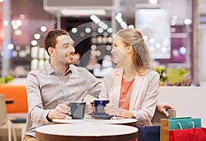 Happy couple with shopping bags drinking coffee