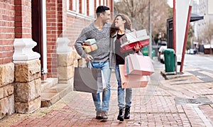 Happy couple, shopping bags and walking in city with gifts for fashion, clothing or buying outdoors. Man and woman in