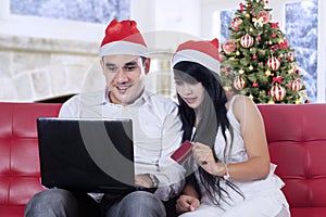 Happy couple shopping online in christmas day