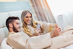 Happy couple shopping online in luxury hotel room