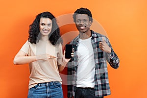 Happy Couple Showing New Smartphone on Orange Background