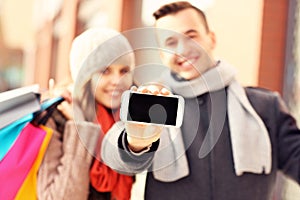 Happy couple showing smartphone while shopping