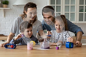 Happy couple and sibling kids engaged in learning chemical game