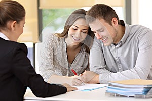 Happy couple signing a contract at office