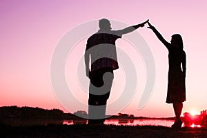 Happy couple silhouette against a sunset romance