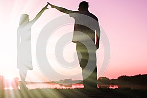 Happy couple silhouette against a sunset romance