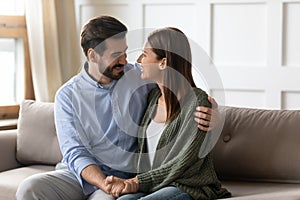 Happy couple sit on couch hugging reunited after fight