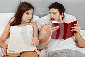 Happy Couple Sitting in Bed Reading Books at Home in Bedroom