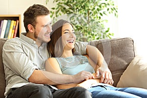 Happy couple sitting on couch and looking away