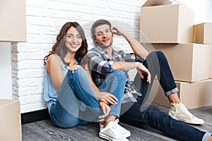 Happy couple sitting on floor around boxes after buying house