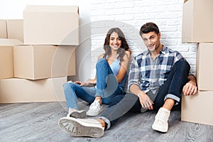 Happy couple sitting on floor around boxes after buying house