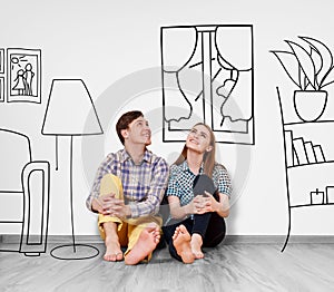 Happy couple sitting on the floor among painted furniture on the wall.