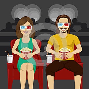 Happy couple sitting in movie theater watching 3D movie, eating popcorn, smiling.