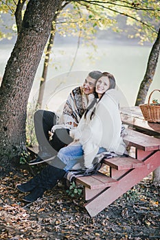 Happy couple sitting near lake in an autumn forest