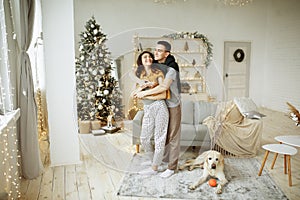 Happy couple is sitting near sofa with a dog, christmas. new year at home. family and date