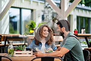 Happy couple sitting outdoors on terrace restaurant, talking.