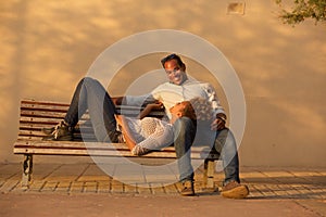 Happy couple sitting on park bench outside
