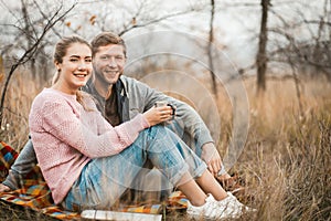 Happy Couple Sitting On Picnic Blanket Outdoors