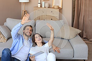 Happy couple sitting and planning new home decoration at home with a tablet