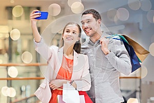 Happy couple with smartphone taking selfie in mall