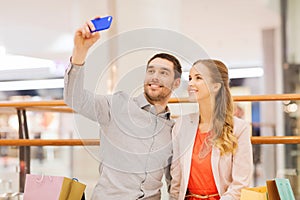 Happy couple with smartphone taking selfie in mall