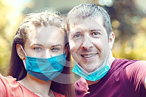 Happy couple smiling with open face masks after lockdown reopening