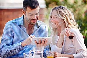Happy couple, smiling and tablet in garden for breakfast, internet and scrolling on social media. Male person, woman and
