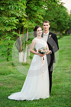 Happy couple smilinging happily on their wedding day in a green garden