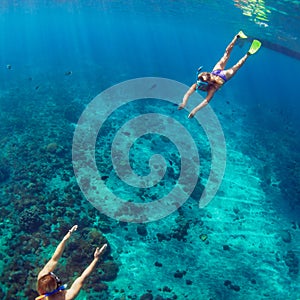 Happy couple snorkeling underwater over coral reef