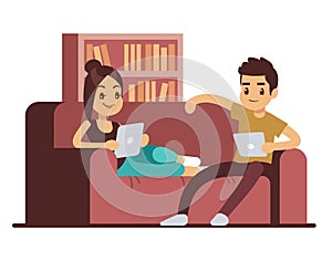 Happy couple on sofa with tablets. Young man and woman relaxing at home
