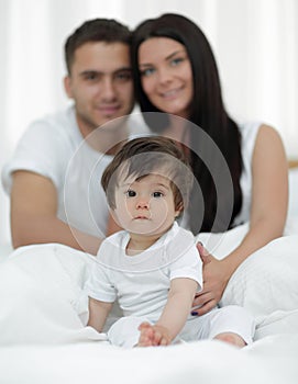 Happy couple and son sitting in bed