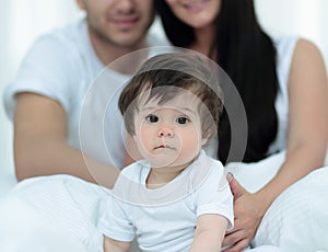 Happy couple and son sitting in bed