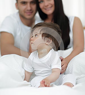 Happy couple and son sitting in bed