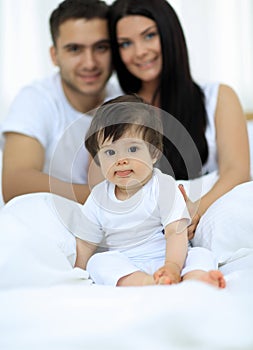 Happy couple and son sitting in bed