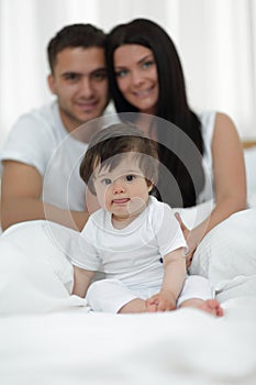 Happy couple and son sitting in bed