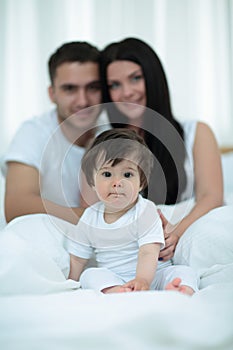 Happy couple and son sitting in bed