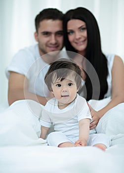 Happy couple and son sitting in bed