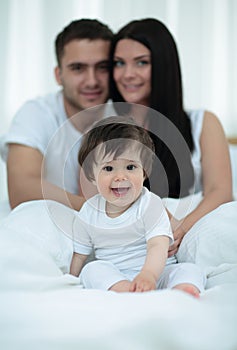 Happy couple and son sitting in bed