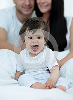 Happy couple and son sitting in bed