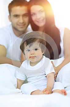 Happy couple and son sitting in bed