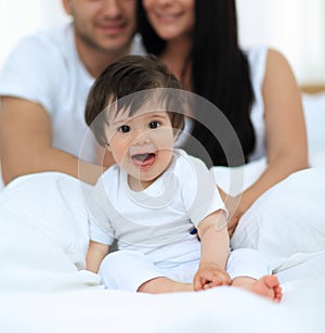 Happy couple and son sitting in bed