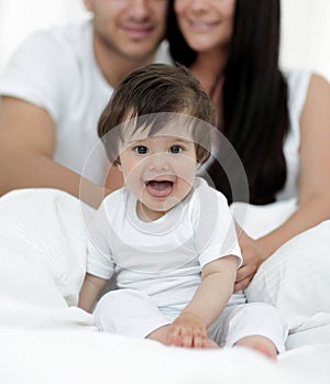 Happy couple and son sitting in bed