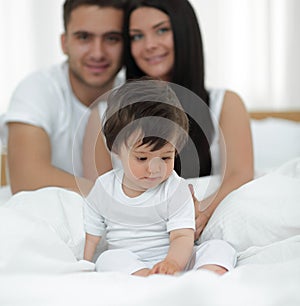 Happy couple and son sitting in bed