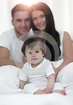 Happy couple and son sitting in bed