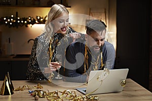 Happy couple spending New Year`s Eve at home with laptop