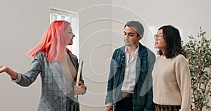 Happy couple stand in empty room while inspecting apartment for rent with real estate agent woman and man look at place