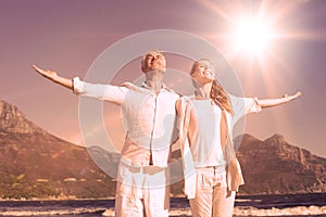 Happy couple standing with arms outstretched at the beach