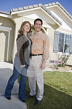Happy Couple Standing In Front Of A New House